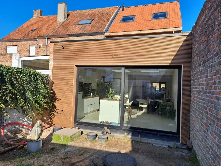Aanbouw met houten gevelbekleding en groot schuifraam